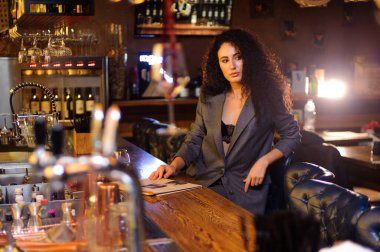 Takım elbiseli şık bir bayan, bir barda tek başına.