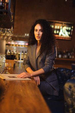 Takım elbiseli şık bir bayan, bir barda tek başına.