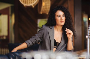 Takım elbiseli şık bir bayan, bir barda tek başına.