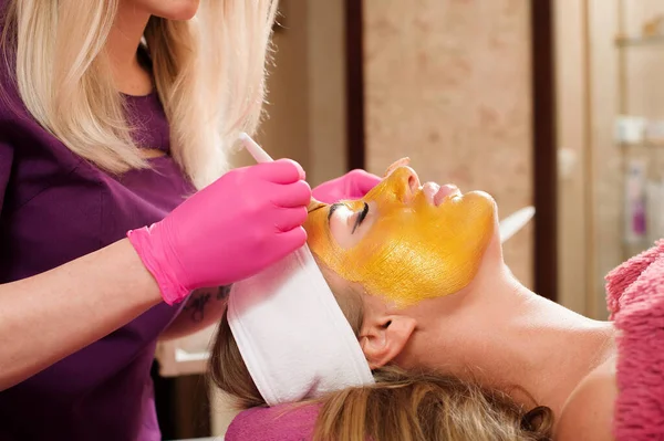 Maska Kosmetyczna Kosmetyczka Nakłada Złotą Maskę Twarz Kobiety Piękna Kobieta — Zdjęcie stockowe