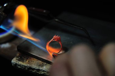 Zanaatkar halka yapmak için bir gaz püskürtme aracı kullanarak çalışıyor