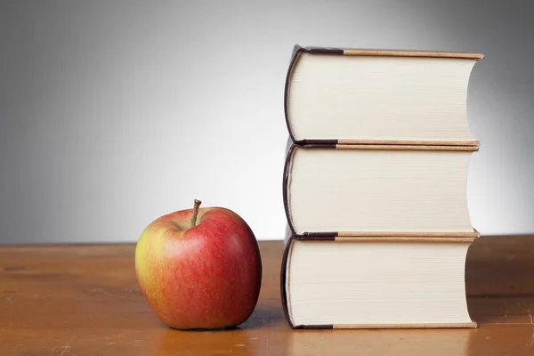 Boeken op een houten tafel, met een appel — Stockfoto