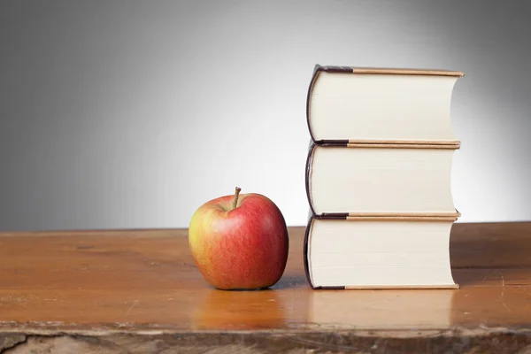 Boeken op een houten tafel, met een appel — Stockfoto