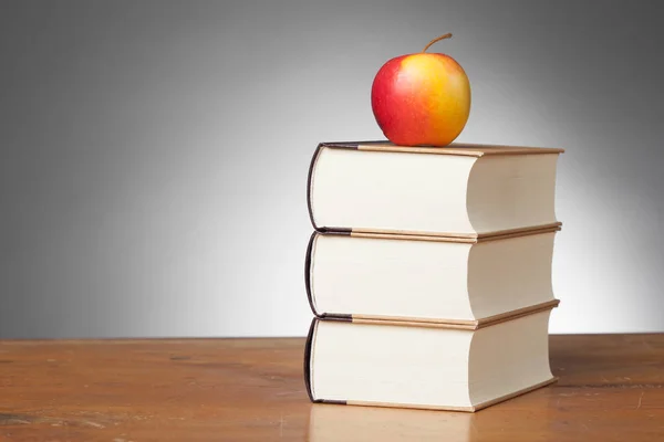 Boeken op een houten tafel, met een appel — Stockfoto