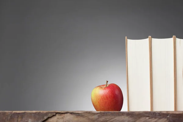 Boeken op een houten tafel, met een appel — Stockfoto