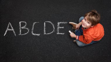Sevimli çocuk, sokak/asfalt onun Abc öğrenme, tebeşir ile