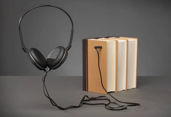 Libros antiguos sobre fondo gris con auriculares, concepto para audiolibros — Foto de Stock