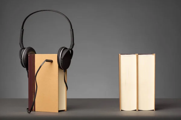 Vintage kirjoja harmaalla pohjalla kuulokkeella, käsite Audio Books — kuvapankkivalokuva