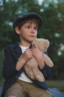 Eski moda Retro giyim, açık havada, tatlı ve şirin ve dalgın genç çocuk ve Teddy Bear