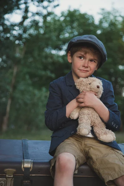 Giovane ragazzo e orsacchiotto in vecchio stile abbigliamento retrò, all'aperto, dolce e carino, guardando in alto — Foto Stock