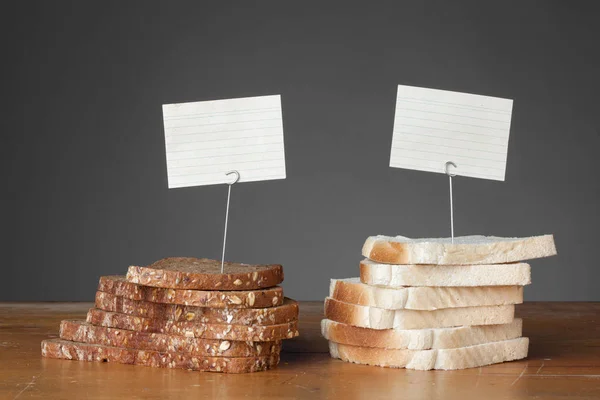 Kleine Serie zum Vergleich von Lebensmitteln - braunes und weißes Brot mit kleinen leeren Schildern / Schildern — Stockfoto