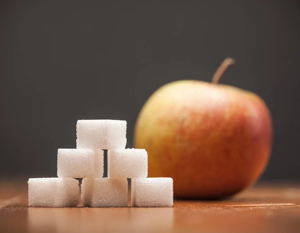 Zuckermengen in Lebensmitteln - Apfel, auf Holztisch und dunklem Rücken — Stockfoto