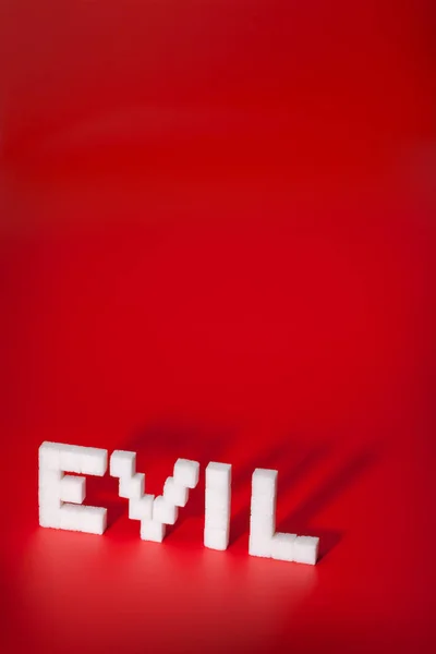 Cukru kształty na czerwono - Word: Evil — Zdjęcie stockowe