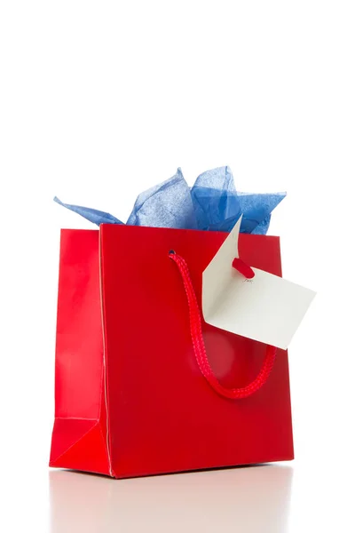 Linda bolsa de regalo roja, con tarjeta, papel azul y espacio de copia, aislado en blanco — Foto de Stock