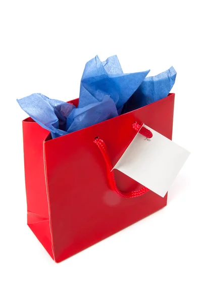 Linda bolsa de regalo roja, con tarjeta, papel azul y espacio de copia, aislado en blanco — Foto de Stock