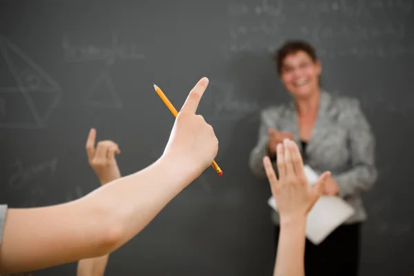 Jovem levantando o braço para fazer uma pergunta na sala de aula . — Fotografia de Stock