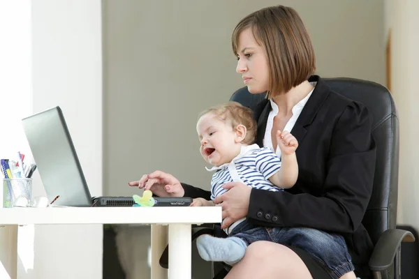 Lovely young working mother and her baby, in her Home Office