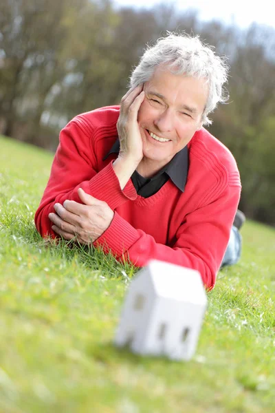 Serie di un pensionato anziano felice, immaginando la sua nuova casa futura con una piccola casa di carta — Foto Stock