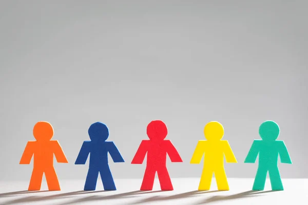 Група Multi кольорові маленькі люди в ряд на сірий фон — стокове фото