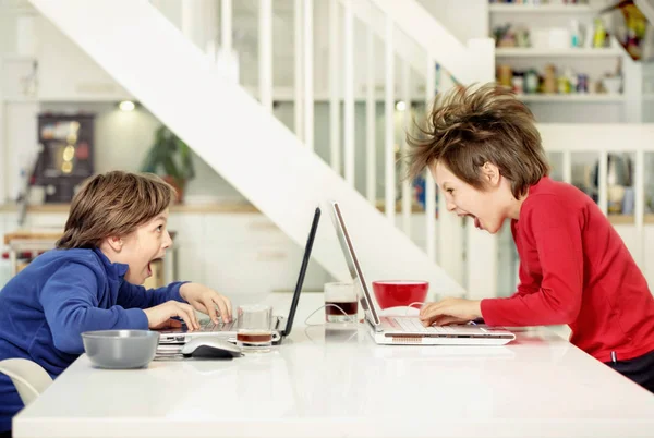 Hermanos en casa en su lugar estilo loft, divirtiéndose en laptops, serios, riendo, totalmente sorprendidos y divertidos —  Fotos de Stock