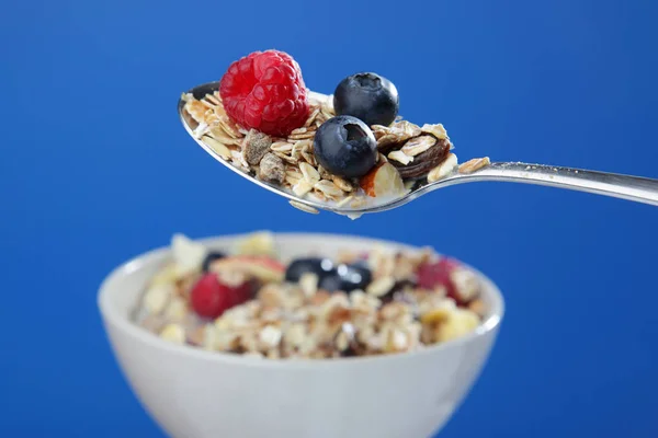 Muesli on a spoon Series, with Milk splashing on Blue Background