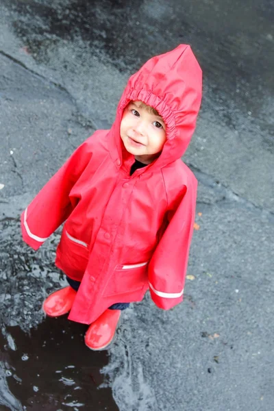 Little Boy in Red Rain Roupas se divertindo em Puddles fora em uma rua em Berlim — Fotografia de Stock