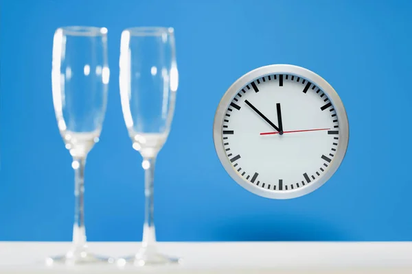 Series of a plain simple clock on New Years Eve, before and during Midnight, on bright blue background: champagne glasses are still Empty — Stock Photo, Image
