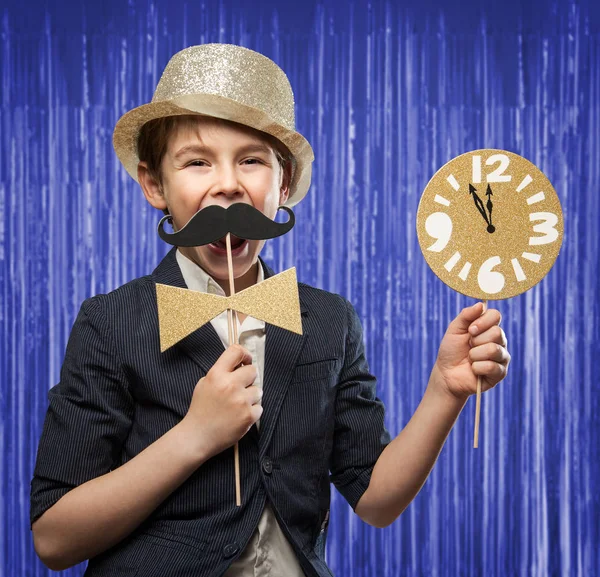 Happy New Year Serie, mit einem 7-jährigen glücklichen Jungen, der mehrere Fotokabinen hält und dabei Spaß hat. mit Uhr Minuten vor Mitternacht vor blau / lila Lametta Hintergrund — Stockfoto