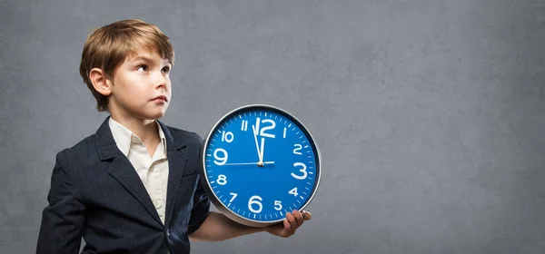 Serious Cute Boy looking up, Holding a blue Big Clock, just minutes before midnight: either, he is warning us that time is running out, or ready to celebrate New Year — Stock Photo, Image