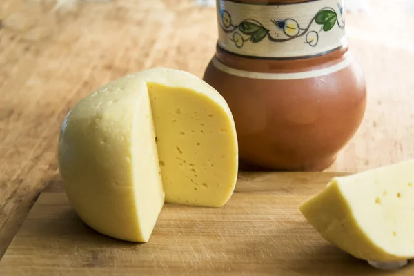 head of cheese gouda sliced piece of jug of milk spoon on  woode