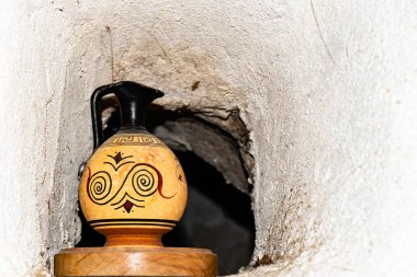 An old ceramic jug on a wooden stand in a small through window in the stone wall between rooms in an old French building