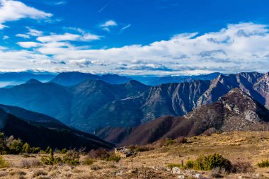 Beautiful captivating landscape of the layered misty hazy French Alps mountain range in Alpes-Maritimes in the afternoon during a sunny day