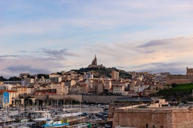 Marseille, France - January 25, 2020: the view of the Basilica Notre-Dame de la Garde and the old port at sunset
