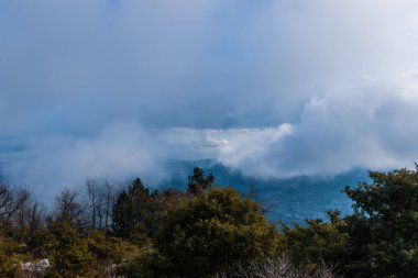 Cote d 'Azur Alpleri' nin bulutlu gökyüzünün altındaki panoramik manzarası ve ufuktaki Akdeniz kıyısı.