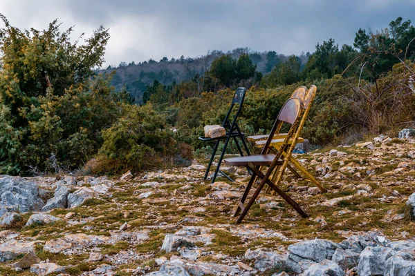 Metallic chairs on a mountain top in the low Alps mountain range under a moody cloudy sky for enjoying the view peacefully