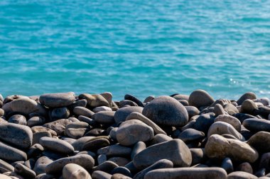 Nice, Fransa 'da bir kumsalda çakıl taşlarının yakın plan çekimi. Arka planda Akdeniz' in turkuaz suyu var.