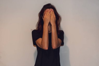 Tanımlanamayan genç, beyaz saçlı, gözlüklü, elinde akıllı bir telefonla yüzünü elinin arkasına saklayan bir kadın.