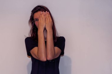 Tanımlanamayan genç, beyaz saçlı, gözlüklü, elinde akıllı bir telefon tutan ve elleriyle yüzünü saklayan ve arkalarından gözetleyen bir kadın.