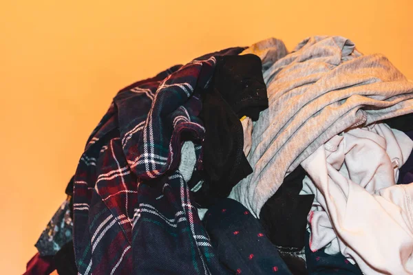 A pile of female clothes against the pastel yellow background under warm light