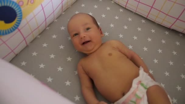 Вид зверху на дитину, яка посміхається в дитячому ліжку. Портативний знімок, фокус зміни камери — стокове відео