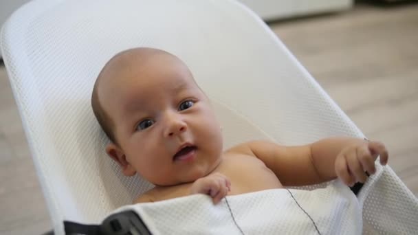 Gyönyörű baba nagy kék szemét, hogy rázta meg egy széken. Kézi lövés — Stock videók