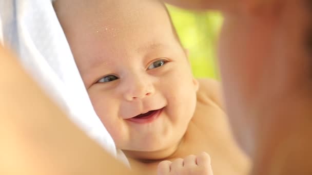 Primer plano de un dulce bebé mirando a la madre y sonriendo felizmente. Disparo de mano — Vídeos de Stock