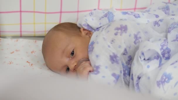 Bebé de ojos azules en una cuna cubierta con una sábana. Disparo de mano — Vídeo de stock
