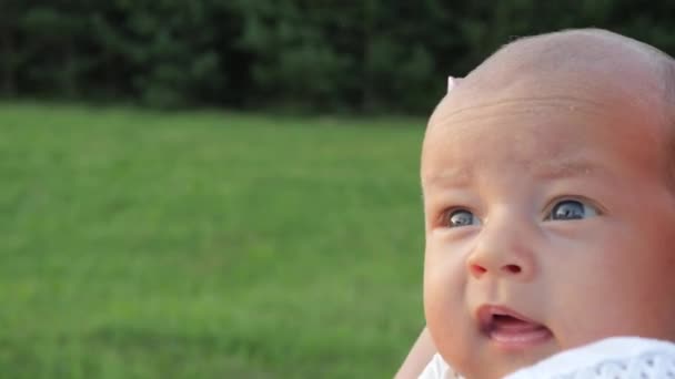 Κοντινό πλάνο πορτρέτο του ένα αστείο μωρό κατά τη διάρκεια του καλοκαιριού με τα πόδια σε ένα πάρκο. Φορητό πυροβολισμό — Αρχείο Βίντεο