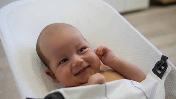 Χαρούμενη μικρό αγόρι κάθεται σε μια καρέκλα μωρού και γελώντας. Φορητό πυροβολισμό — Αρχείο Βίντεο