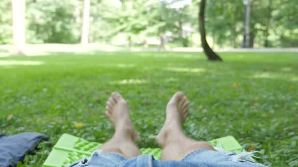 Pés descalços de um homem caucasiano deitado em um gramado em um parque de verão — Vídeo de Stock