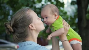 Havadaki bir bebek yetiştirme, öpüşme ve güldüğünü yapma genç anne