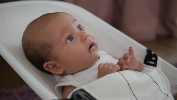 Amazed baby boy with wide-open eyes being rocked in a chair. handheld shot — Stock Video