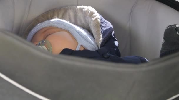 Warmly clothed baby sleeping in a carriage. Handheld shot, camera moves — Stock Video