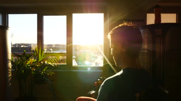 Vue floue d'un jeune homme qui s'entraîne dans une salle de gym sous les rayons du soleil par la fenêtre. Panoramique de droite à gauche et en arrière — Video